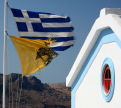 Symi - the twin symbols of Greece, the Naitional flag and the flag of the Greek Orthodox Church, fly proudly in the stiff breeze at Agios Georgios Drakondiotis on the path from Nimborio to Yialos
