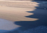 cliff-top shadow of low winter sun on Rhossili beach (note the size of the people on the beach)